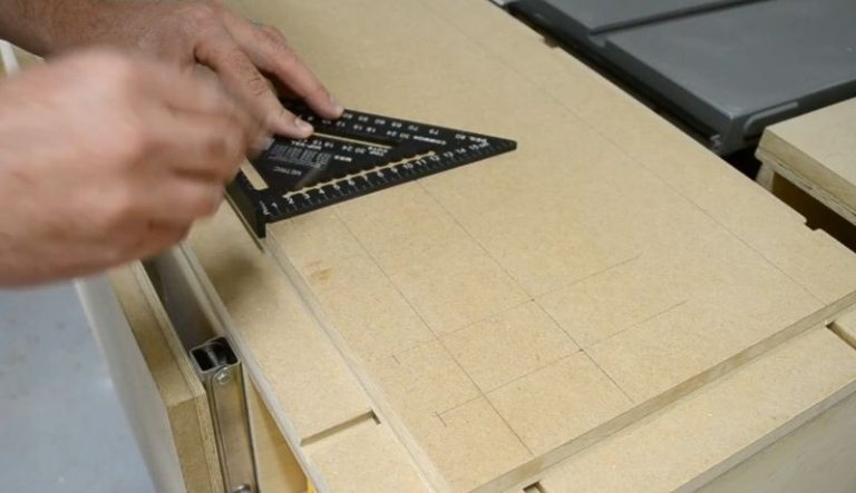 Woodworker using a square to draw precise layout lines on a plywood board.