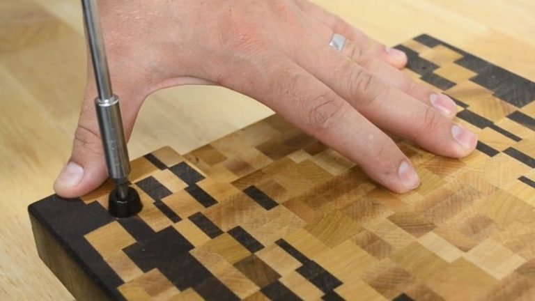 Installing rubber feet on a finished ombré end grain cutting board.
