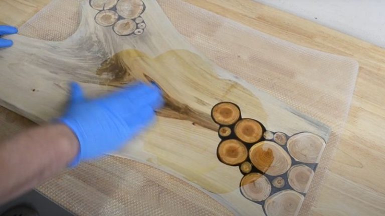 Applying food-safe oil to a walnut cutting board with a cloth.