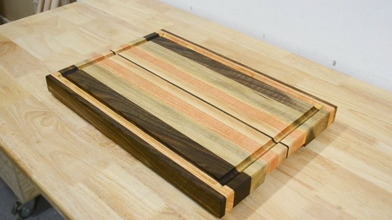 Finished oiled edge grain cutting board with juice groove and handles.