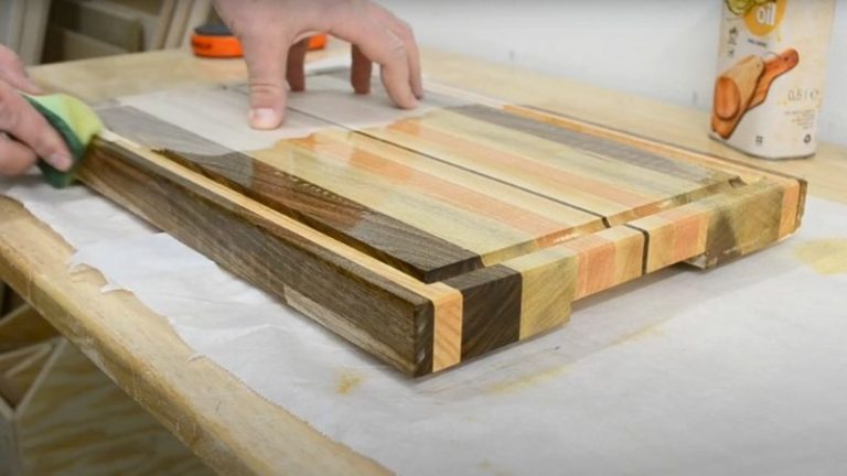 Applying food-safe oil to an edge grain cutting board with a cloth.