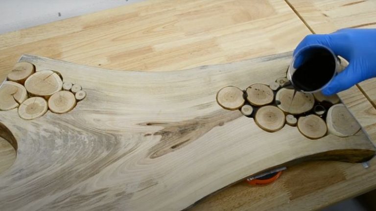 Pouring epoxy into gaps and voids between cherry wood cookies on a walnut board.