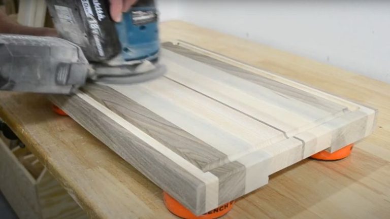 Sanding an edge grain cutting board with an orbital sander.