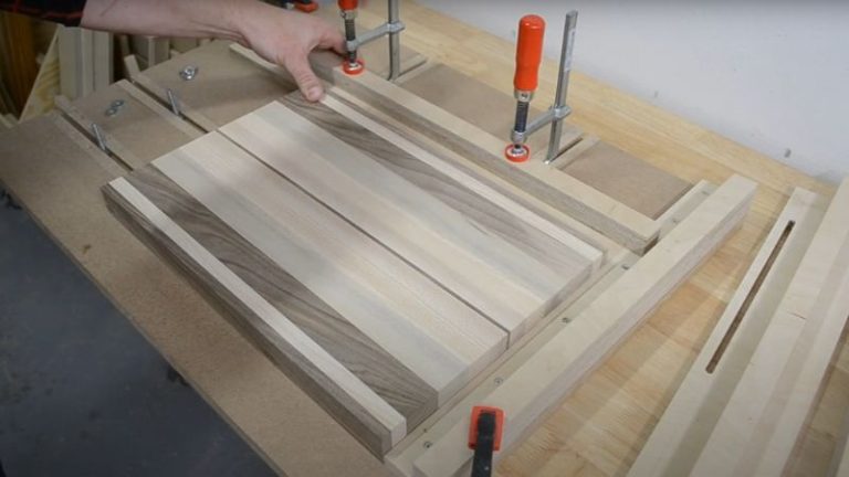 Securing a cutting board into a juice groove jig before routing.
