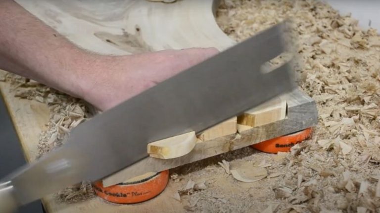Trimming excess wood from glued inlays using a hand saw.