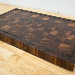 DIY walnut end grain cutting board with juice groove, beveled edges, and rubber feet ready for use.