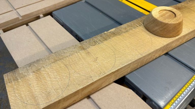 Marking bowl circles and centers on an oak slab using another bowl as reference.