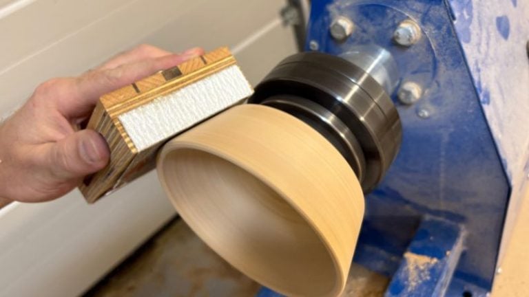 Using a sanding block to carefully smooth the rim of the bowl