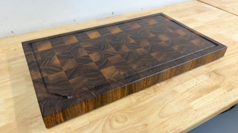 Finished walnut end grain cutting board with juice groove and beveled edges ready for use.