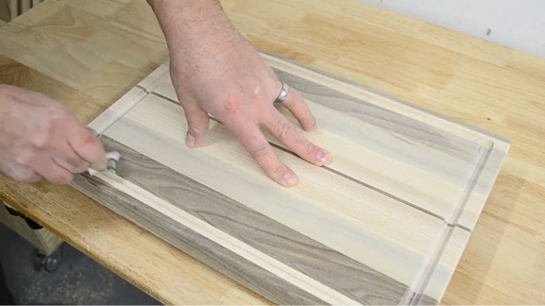Close-up of a hand lightly sanding inside a juice groove with rolled sandpaper after routing.