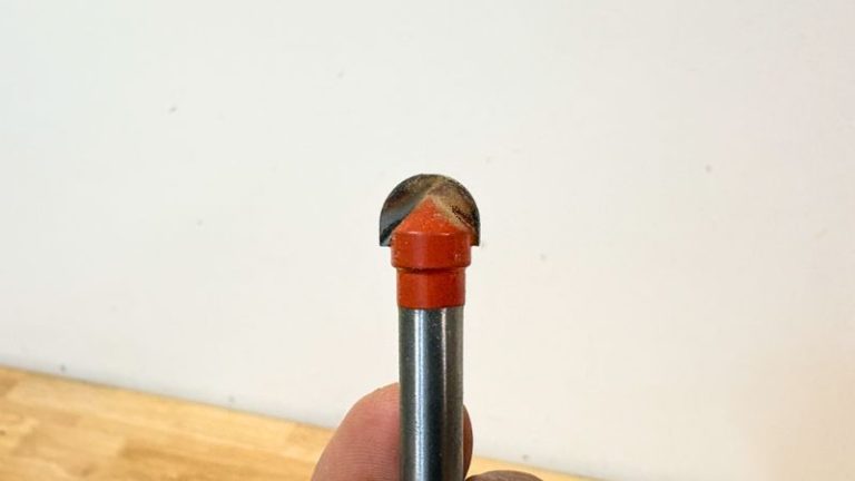 Handheld trim router with a 10 mm core box bit next to a cutting board ready for routing a juice groove.