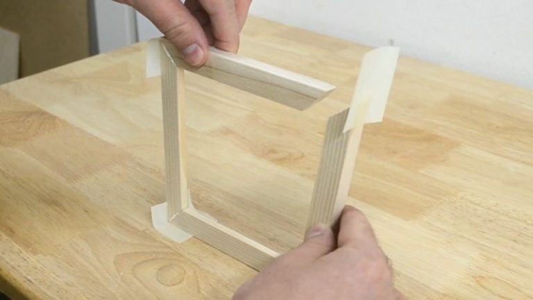 Picture frame glued and held together with painter’s tape and a strap clamp during drying.