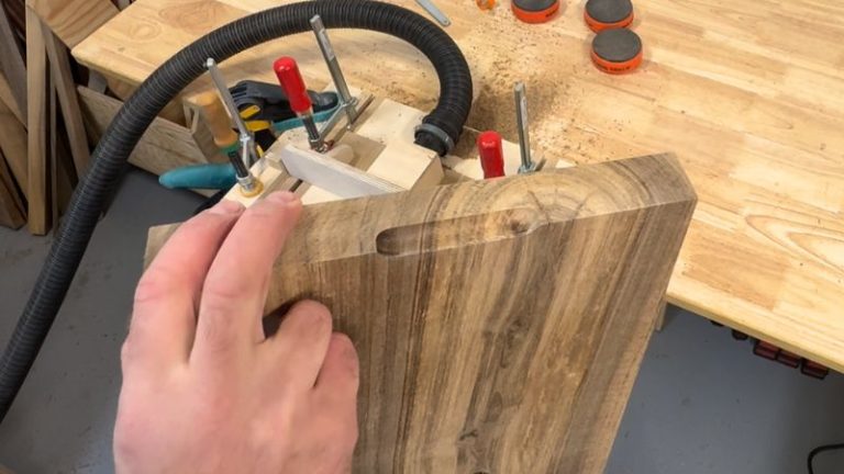 Close-up of a walnut cutting board with beveled edges and routed side handle finished.