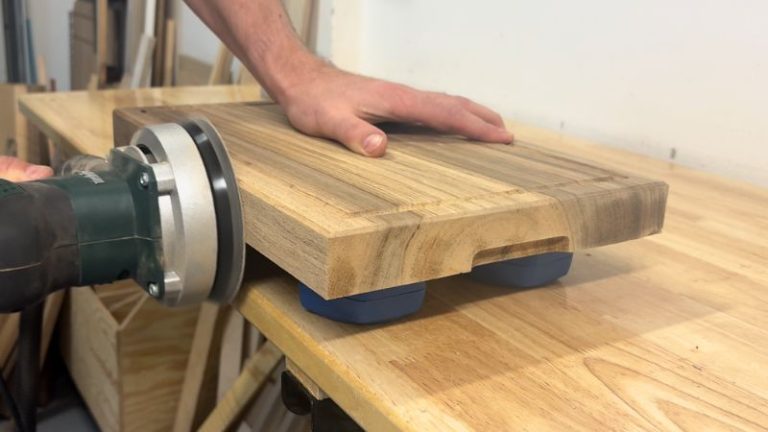 Sanding a walnut cutting board with an orbital sander, progressing through grits from 80 to 300.