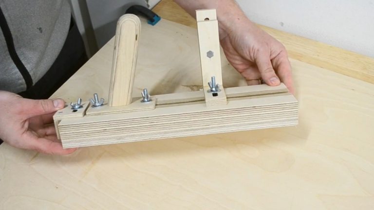 Close-up of a DIY table saw thin strip jig showing the T-track, adjustable hold-down clamp, and back stopper.