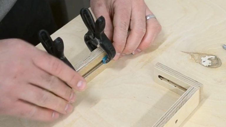 Adjustable hold-down arm made from plywood and thinner MDF assembled around a bolt and wing nut.