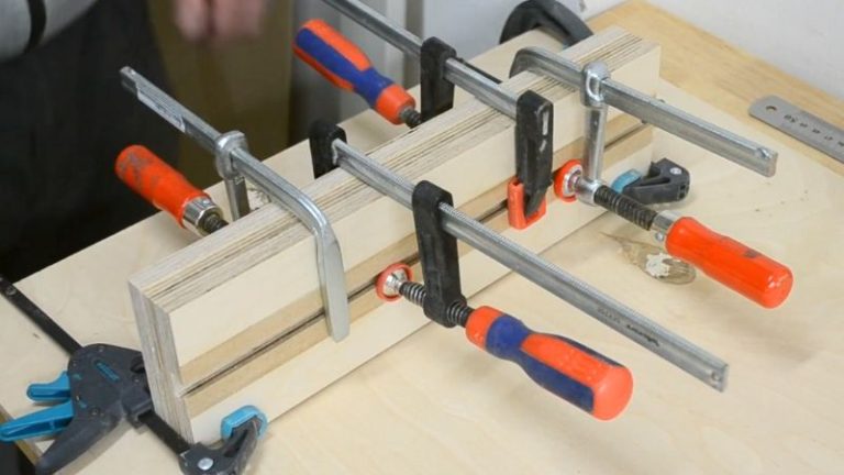 MDF strips being glued and clamped into the routed dadoes to form a T-track on the jig base.