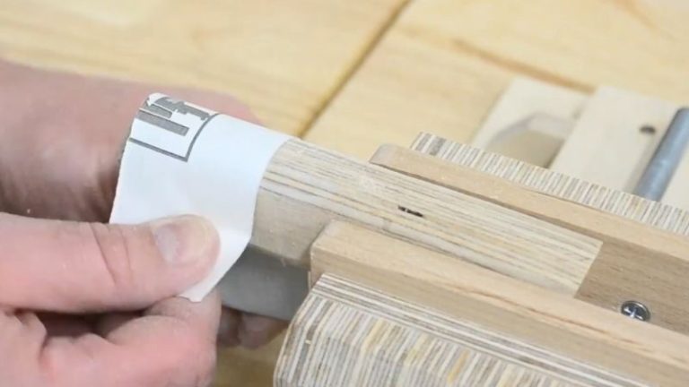 Shaping the plywood handle on a sander to round the edges and improve the grip.