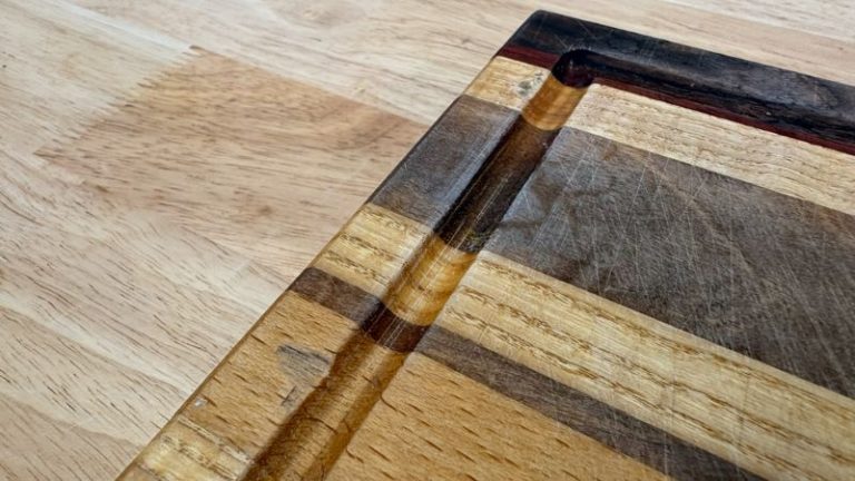 Tear-out and rough spots around a cutting board juice groove before rerouting and refinishing.