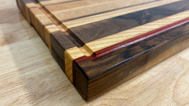 Finished restored edge grain cutting board on a kitchen countertop with rubber feet installed, sitting flat and stable.