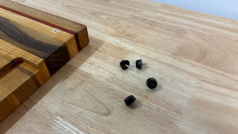 Rubber feet and screws from a cutting board placed in a tray to keep hardware organized during refinishing.