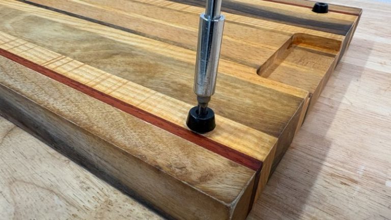 Removing rubber feet from the underside of a cutting board before refinishing.