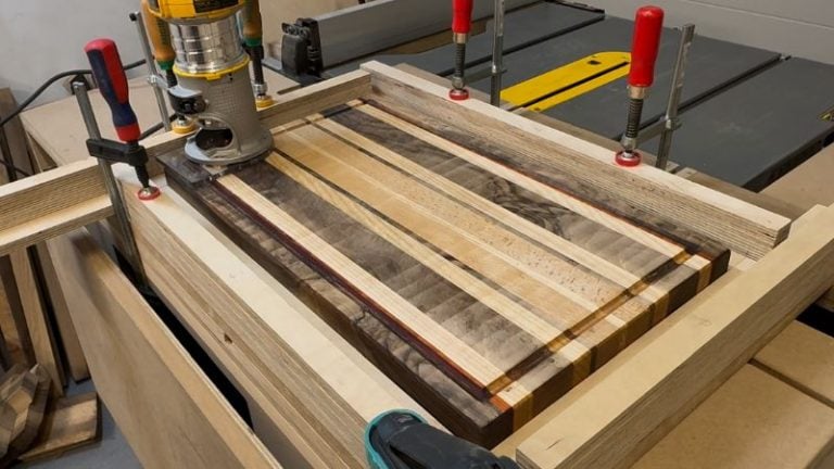 Cutting board clamped inside a juice groove jig before rerouting the groove during refinishing.