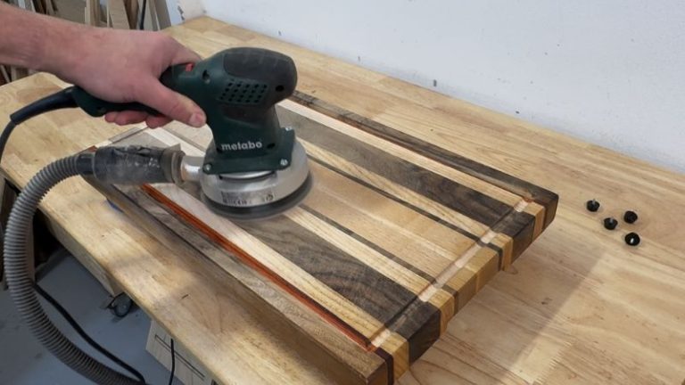 Orbital sanding a cutting board surface after router flattening to remove surfacing bit marks.