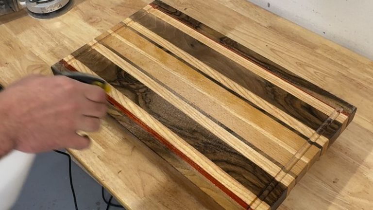 Spraying a light mist of water on a cutting board to raise the grain before final sanding.