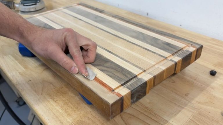 Hand sanding the juice groove of a cutting board after rerouting to smooth the groove edges.