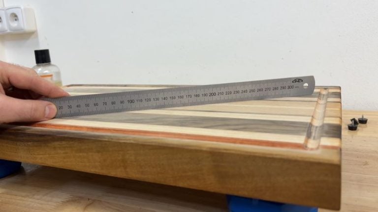 Checking a cutting board for flatness with a straight ruler and looking for light gaps under the edge.