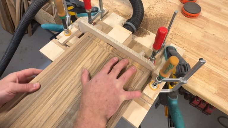 Cutting an underside finger grip on a cutting board at a router table using a cove bit and multiple light passes.