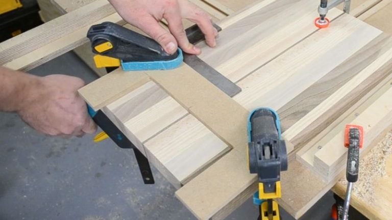 Handle jig clamped to the underside of a cutting board, centered on the side and ready for routing an underside finger grip.