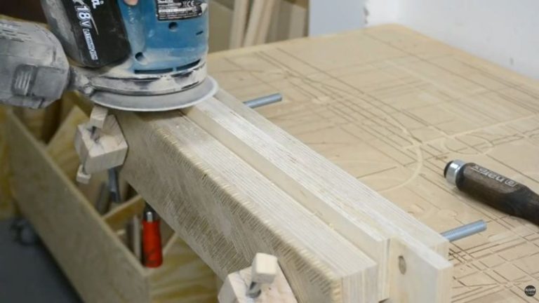 Sanding laminated plywood frame parts with an orbital sander before assembling the cart frame.