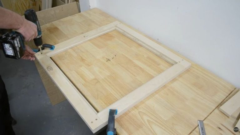 Sanding a finished plywood frame and reinforcing the corners with screws.