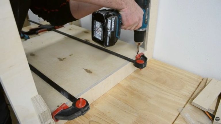 Clamping a plywood inside panel between two support frames before screwing it in place.
