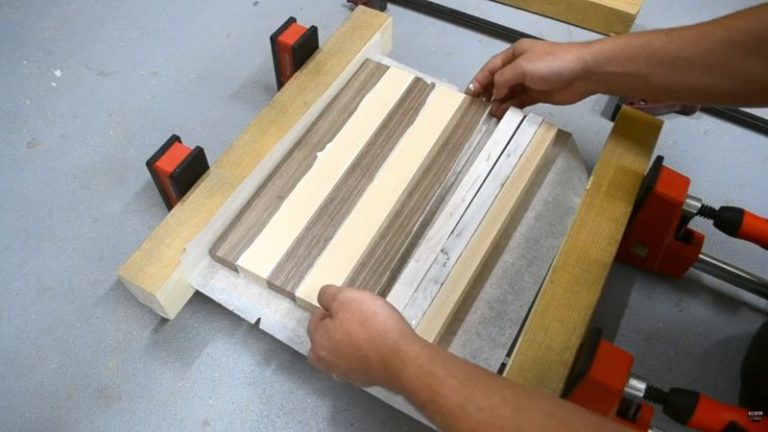 Applying wood glue to beech and walnut strips before clamping them into a panel for a wooden chess board build.