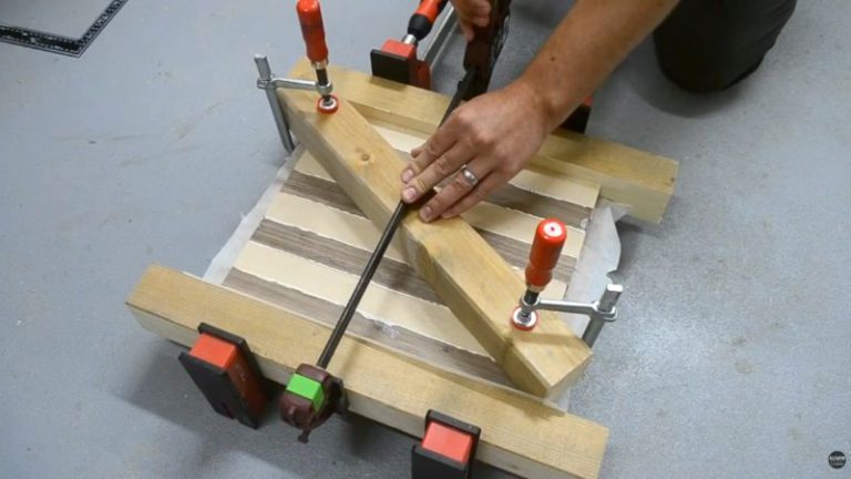Clamping glued beech and walnut strips into a flat panel using bar clamps for a DIY wooden chess board.