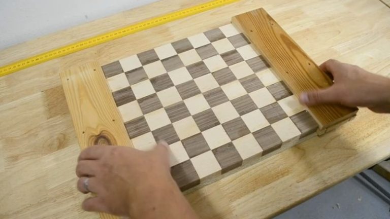 Gluing sacrificial wood pieces to both ends of a chessboard panel to prevent planer snipe and tear-out.