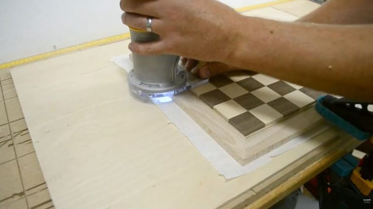Beveling the edges of a chessboard frame using a router jig to soften edges and add a finished look.