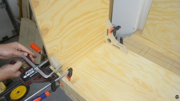 Corner clamps holding a divider in place on the lumber cart base before predrilling and screwing it down.