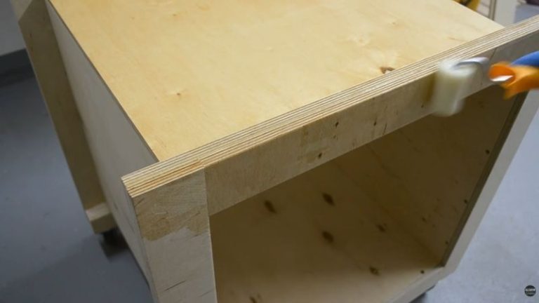 Applying varnish to the plywood body of a DIY planer stand with storage.