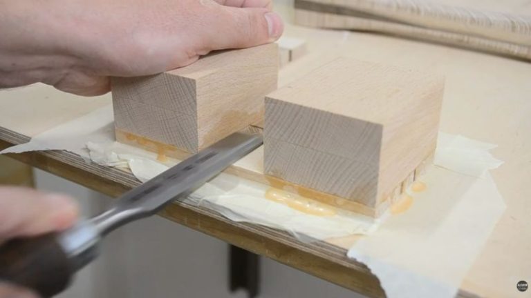 Gluing the first head side panel to the beech head blocks and cleaning glue squeeze-out inside the handle opening with a chisel.