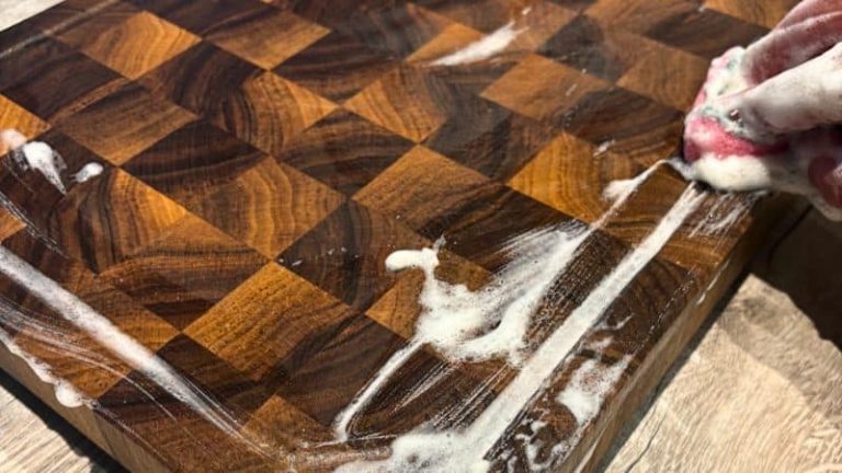 Cleaning the juice groove of a walnut cutting board with soap during regular daily maintenance.