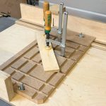 DIY table saw angle jig mounted on a table saw sled with a workpiece clamped at an angle.