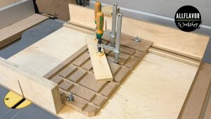 DIY table saw angle jig mounted on a table saw sled with a workpiece clamped at an angle.