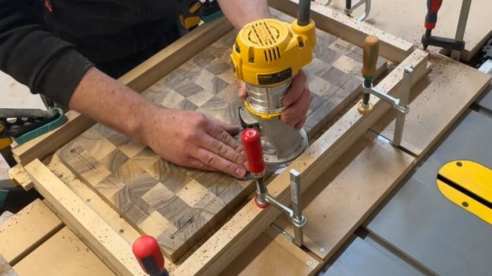 Router cutting a juice groove on an end grain board, taking shallow passes along the inside border.
