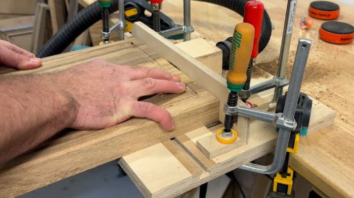 Routing a side handle into a walnut cutting board on a router table using a cove bit.